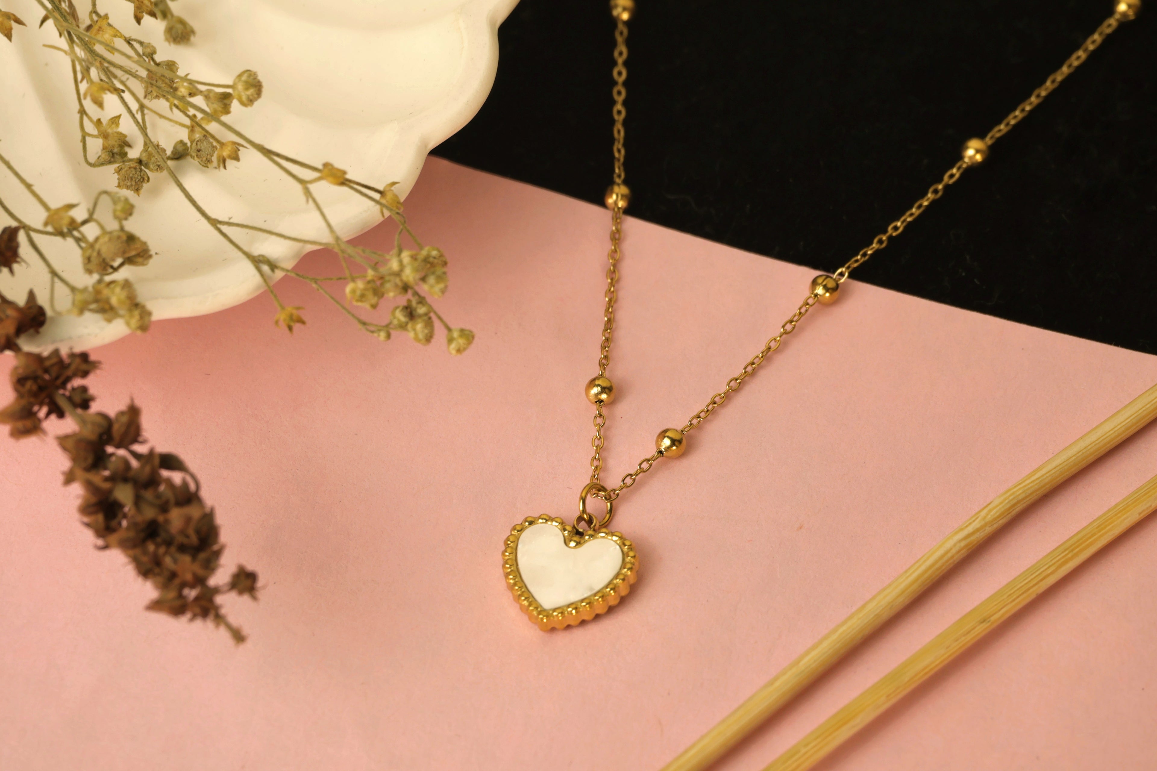 Delicate gold chain necklace with a small heart-shaped pendant.